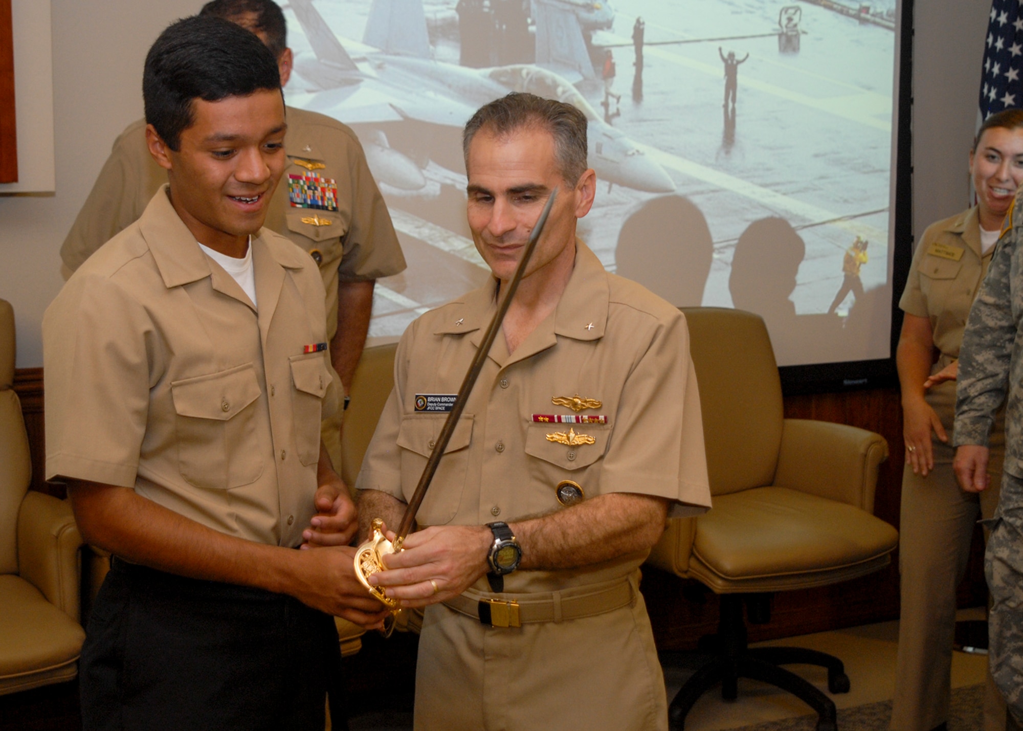 U.S. Navy Rear Adm. Brian Brown, deputy commander, Joint Functional Component Command for Space, and Apprentice Seaman Recruit Gustavo Aceves, prepare to cut the cake using a ceremonial sword during JFCC Space’s celebration of the U.S. Navy’s 239th birthday, Oct. 14, 2014, at Vandenberg Air Force Base, Calif.  It is Navy tradition to have the command’s most senior Sailor share the honor of cutting the birthday cake with the youngest Sailor. (U.S. Air Force photo by Capt. Nicholas Mercurio/Released)