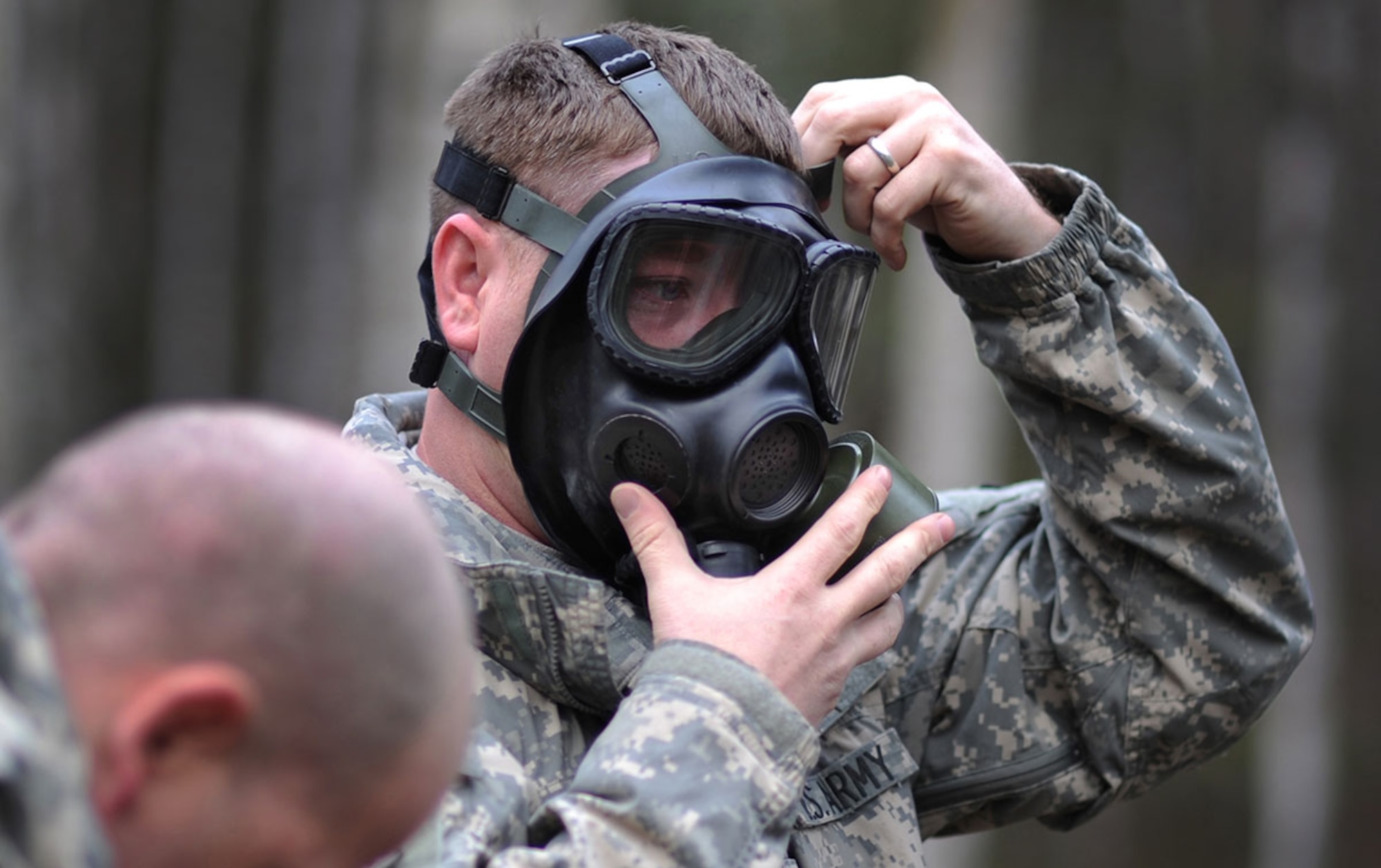 A soldier assigned to Headquarters and Headquarters Detachment, 59th Signal Battalion, checks the seal on his protective mask during Nuclear Biological Chemical training on Joint Base Elmendorf-Richardson, Alaska, Thursday, 2014. The training culminated with masked Soldiers entering a sealed chamber filled with CS, then removing their protective gear to promote confidence in their equipment. CS, technically known as 0 chlorobenzalmalononitrile, is a solid white powder mixed with a dispersal agent and commonly referred to as tear gas. (U.S. Air Force photo/Justin Connaher)