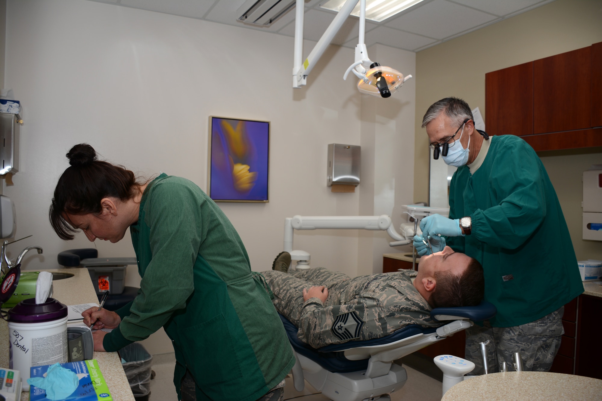 Master Sgt. Melissa Long, Dental Hygienist in the 507th Medical Squadron, annotates
the patient's dental record while assisting Lt. Col. (Dr.) Randall Griffin
during an annual exam on Oct. 4  2014 at Tinker Air Force Base.  On a
typical UTA weekend, the dental team examines approximately 50 patients.  (U.S. Air Force photo/Staff Sgt. Lauren Gleason)
