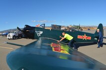 TRAVIS AIR FORCE BASE, Calif. -- An Air Force Reservist pushes a vintage aircraft to its parking spot Oct. 18, 2014, during the 9th Annual "Mustangs and More" aircraft and car show at the Nut Tree Airport in Vacaville, Calif. Members of the Air Force Reserve's 349th Air Mobility Wing volunteered to support the event in which proceeds from ticket sales went to support the Travis Air Force Base Heritage Center and the maintenance of display aircraft there. This year's event hosted more than 40 vintage aircraft  as well as classic and new Ford Mustangs and other muscle cars. (U.S. Air Force photo/2nd Lt. Stephen J. Collier)