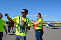 TRAVIS AIR FORCE BASE, Calif. -- Senior Airman Melanie Ivey works with other members of the Air Force Reserve's 349th Air Mobility Wing to coordinate aircraft parking Oct. 18, 2014, during the 9th Annual "Mustangs and More" aircraft and car show at the Nut Tree Airport in Vacaville, Calif. This year's event hosted more than 40 vintage aircraft as well as classic and new Ford Mustangs and other muscle cars. All of the proceeds from ticket sales went to support the Travis Air Force Base Heritage Center and the maintenance of display aircraft there. (U.S. Air Force photo/2nd Lt. Stephen J. Collier) 
