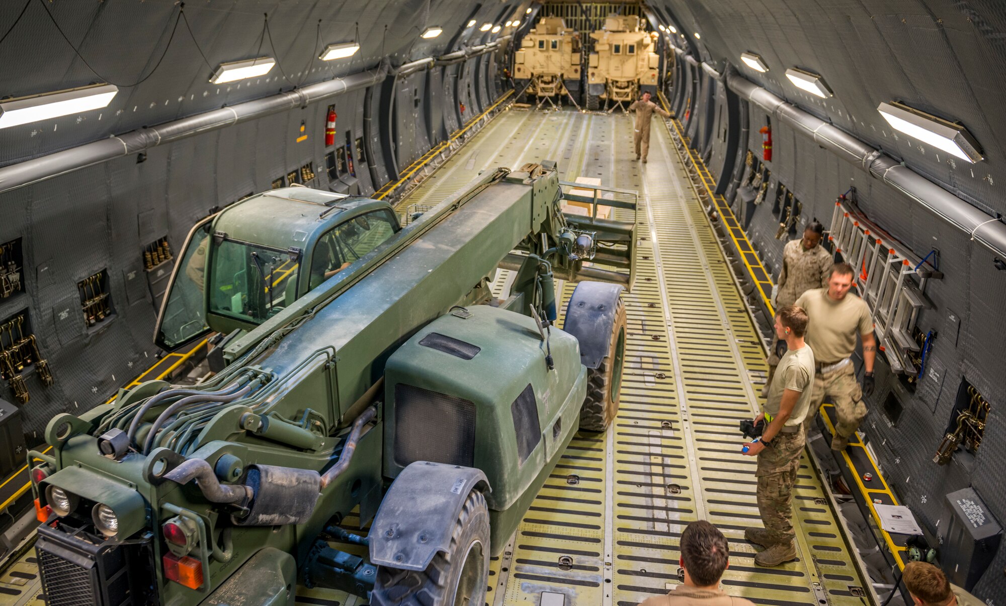 Airmen from the 9th Airlift Squadron and 455th Expeditionary Aerial Port Squadron with Marines from the Marine Expeditionary Brigade prepare to load vehicles into a C-5M Super Galaxy Oct. 6, 2014 at Camp Bastion, Afghanistan. Airmen and Marines loaded more than 266,000 pounds of cargo onto the C-5M as part of retrograde operations in Afghanistan. Aircrews for the retrograde operations, managed by the 385th Air Expeditionary Group Detachment 1, surpassed 11 million pounds of cargo transported in a 50-day period. During this time frame, crews under the 385th AEG broke Air Mobility Command's operational cargo load record five times. The heaviest load to date is 280,880 pounds. (U.S. Air Force photo by Staff Sgt. Jeremy Bowcock)