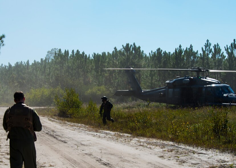 A 41st Rescue Squadron special missions aviator, right, runs to the rescue of the simulated aircraft survivor U.S. Air Force Capt. (Dr.) James Mikolajczak, 75th Fighter Squadron flight surgeon, during a combat search and rescue task force exercise Oct. 22, 2014, in Homerville, Ga.  Members of the 75th Fighter Squadron and the 41st Rescue Squadron joined forces to provide close air support and to rescue a simulated aircraft crash survivor. (U.S. Air Force Airman 1st Class Ceaira Tinsley/Released)