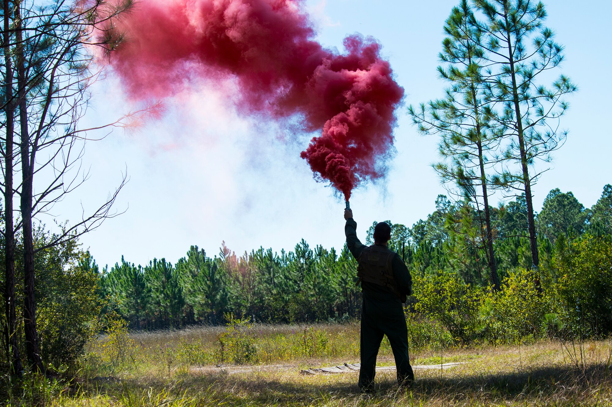 U.S. Air Force Capt. (Dr.) James Mikolajczak, 75th Fighter Squadron flight surgeon, sets off a smoke signal during a combat search and rescue task force exercise Oct. 22, 2014, in Homerville, Ga. The smoke was a distress signal that pinpointed Mikolajczak’s location to the 41st Rescue Squadron.  (U.S. Air Force Airman 1st Class Ceaira Tinsley/Released)