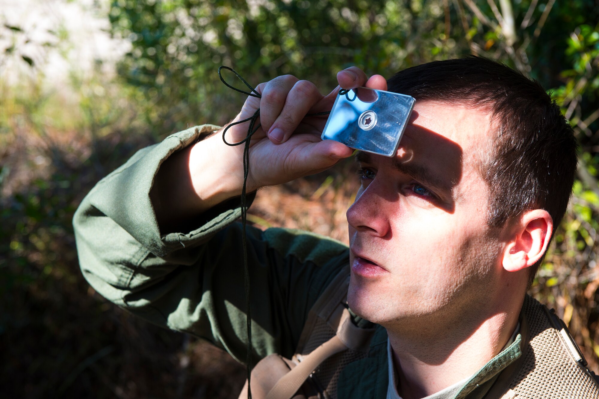 U.S. Air Force Capt. (Dr.) James Mikolajczak, 75th Fighter Squadron flight surgeon, uses a signal mirror to reflect light during a combat search and rescue task force exercise Oct. 22, 2014, in Homerville, Ga. Mikolajczak used the mirror to reflect sunlight using short and long flashes that pilots recognize as a distress call. (U.S. Air Force Airman 1st  Class Ceaira Tinsley/Released)