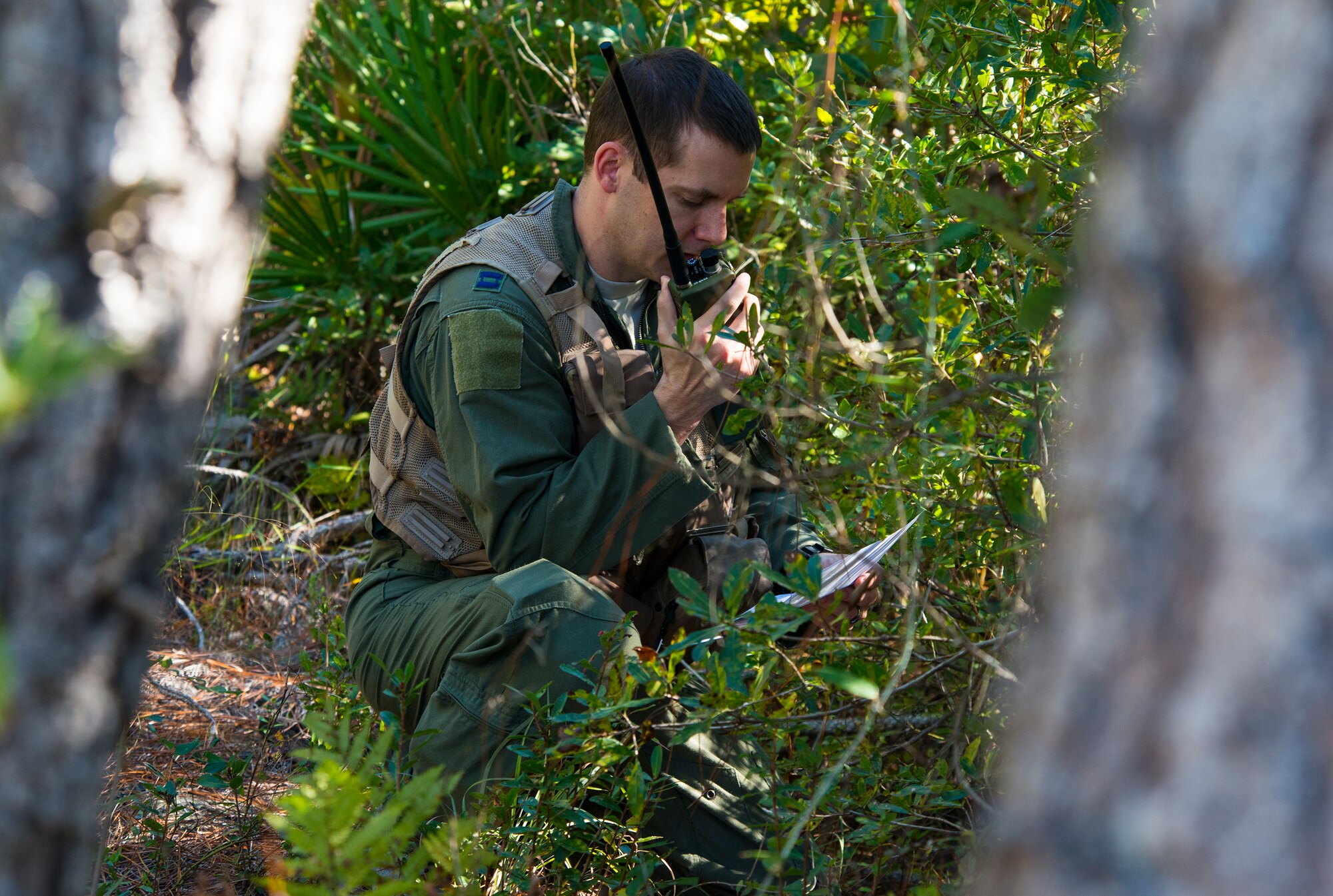 U.S. Air Force Capt. (Dr.) James Mikolajczak, 75th Fighter Squadron flight surgeon, radios for help during a combat search and rescue task force exercise Oct. 22, 2014, in Homerville, Ga. Mikolajczak simulated an F-18 Hornet fighter pilot who survived after his plane was shot down in enemy territory. (U.S. Air Force Airman 1st Class Ceaira Tinsley/Released)