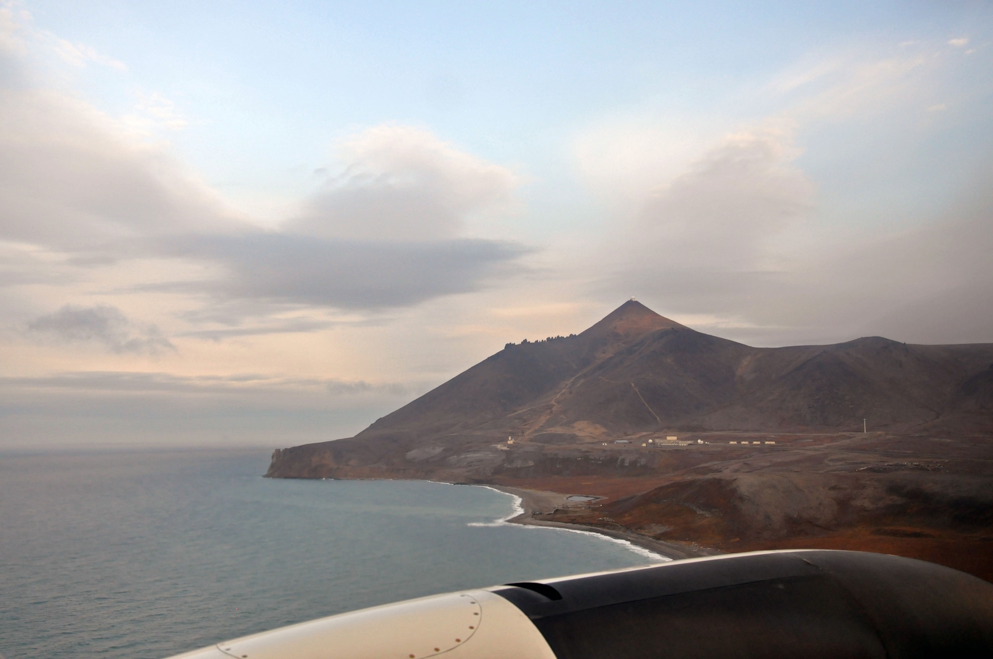 Looking out the window of a U.S. Air Force C-12 at Tin City Long Range Radar Site, Alaska, October 1, 2014. The radar sits on top of the highest peak with the living quarters for the team working at the site and the gravel airstrip below. The Tin City LRRS, along with 14 additional radar sites across the rugged terrain of Alaska, scan the airspace above 24 hours a day, seven days a week, 365 days per year, searching for potential threats. Together with the men and women of the Pacific Air Forces Regional Support Center at Joint Base Elmendorf-Richardson, Alaska, this team makes up the unsung heroes that protect our nation’s northern and western borders. (U.S. Air Force photo/Capt. Anastasia Wasem)