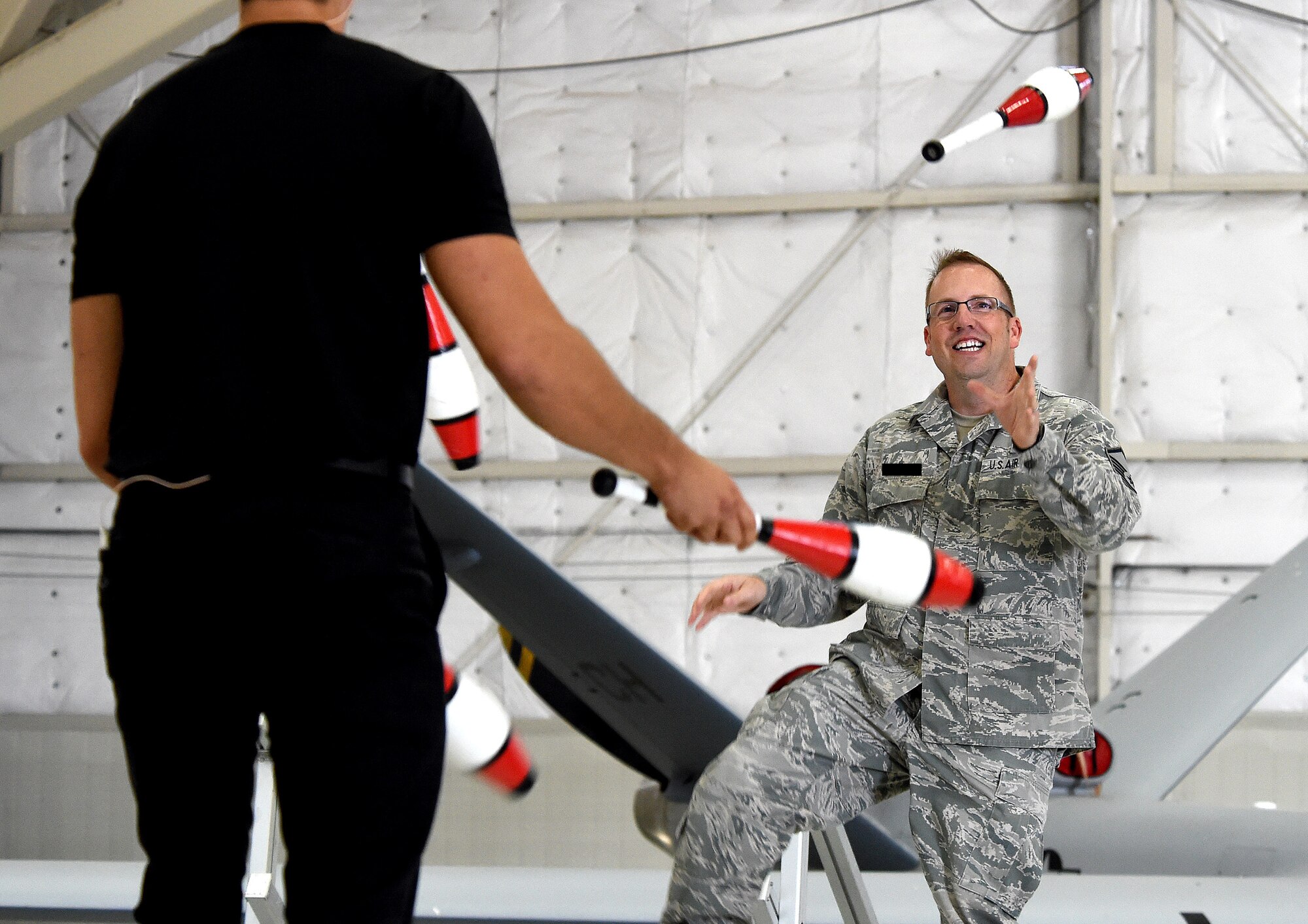 Master Sgt. Douglas, 17th Reconnaissance Squadron, juggles with entertainer, Jeff Civillico, during his performance at Creech Air Force Base, Nevada, Oct. 17, 2014. The entertainment and food event was the latest USO-sponsored show to lift the spirits of America’s troops and their families, which the USO has provided since its creation in 1941. (Last names have been withheld for security purposes). (U.S. Air Force illustration by Tech. Sgt. Shad Eidson/Released)
