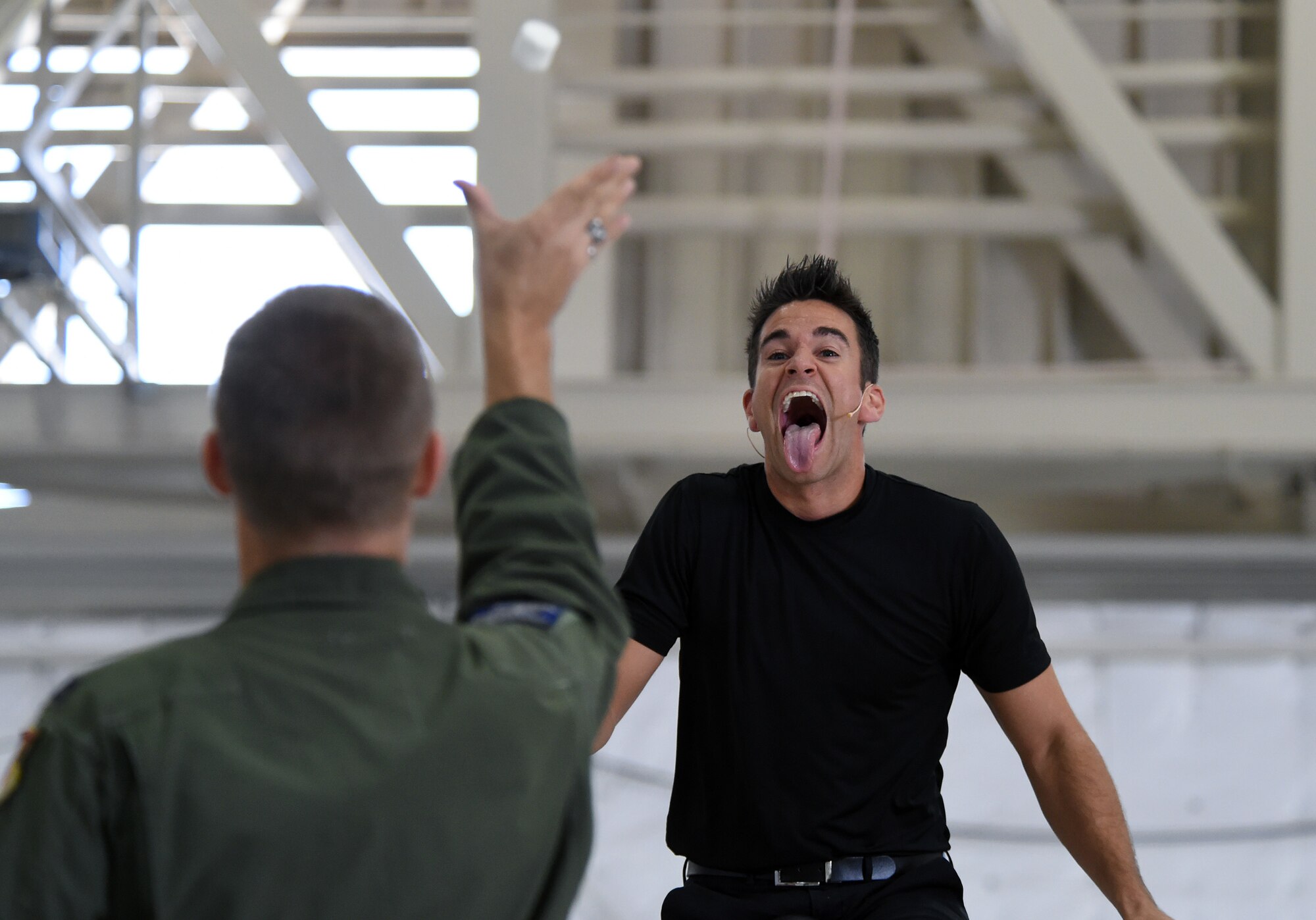Capt. Travis, 42nd Attack Squadron director of staff, tosses a marshmallow to entertainer, Jeff Civillico, who is riding a unicycle during his performance at Creech Air Force Base, Nevada, Oct. 17, 2014. Airmen were pulled from the audience and included in most parts of the juggling and comedy routine. (Last names have been withheld for security purposes). (U.S. Air Force photo by Tech. Sgt. Shad Eidson/Released)