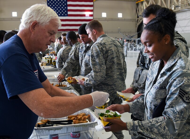 USO volunteer Bill Finch serves food to Airmen before a morale event at Creech Air Force Base, Nevada, Oct. 17, 2014. Along with free food, Airmen were entertained by Jeff Civillico, who performed a juggling and comedy routine as part of a new Freedom Friday Concert Series the USO is sponsoring at Creech. (U.S. Air Force photo by Tech. Sgt. Shad Eidson/Released)