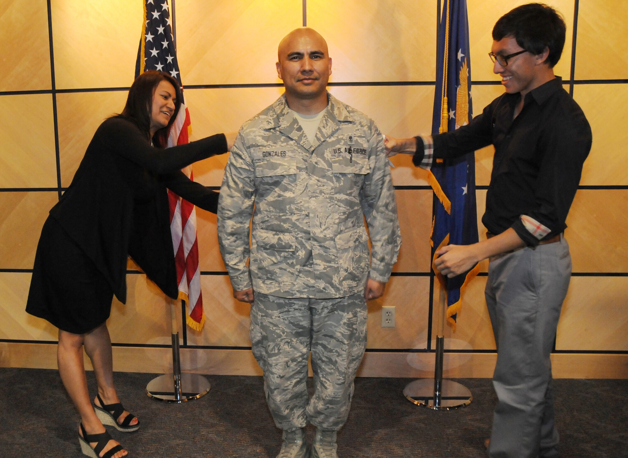 Chief Master Sgt. Juan Gonzales has his stripes put on by his son and daughter during his promotion ceremony at the Colonel Hugh B. Correll Headquarters Facility auditorium at Ebbing Air National Guard Base, Fort Smith, Ark., Oct. 5, 2014. Gonzales is the noncommissioned officer in charge of the 188th Medical Group. (U.S. Air National Guard photo by Airman 1st Class Cody Martin/released)