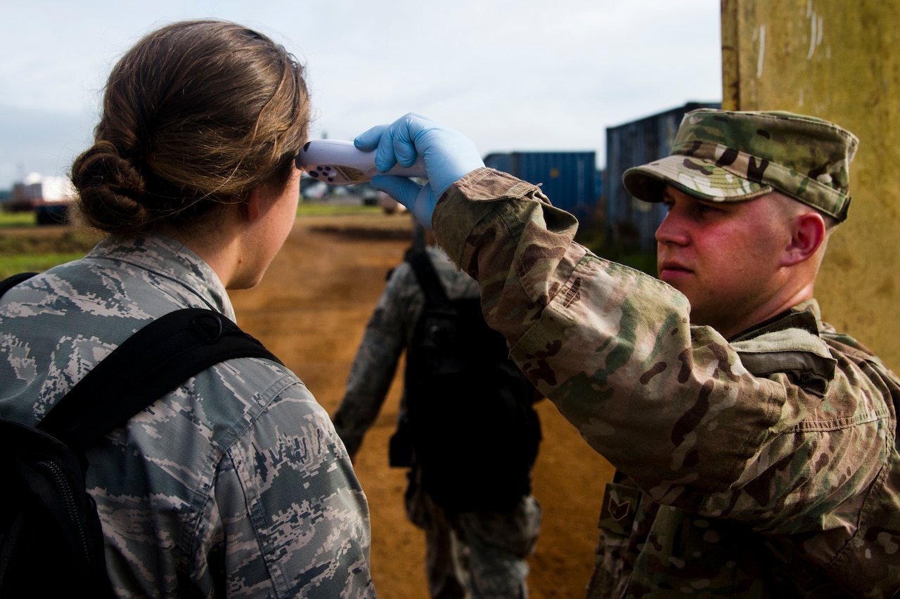 A U.S. airman assigned to the Joint Task Force-Port Opening team at Roberts International Airport in Monrovia, Liberia, checks the temperature of military personnel entering the airport as a safety precaution during Operation United Assistance, Oct. 16, 2014. U.S. Air Force photo by Staff Sgt. Gustavo Gonzalez