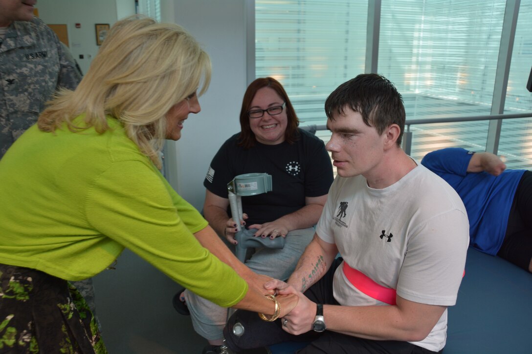 Dr. Jill Biden greets Army Sgt. Cory Muzzy and his wife, Michelle, at the Center for the Intrepid, Brooke Army Medical Center’s outpatient rehabilitation center, Oct. 22, 2014. Muzzy was injured in an artillery training accident at Fort Bragg, N.C., in February, losing most of his vision, his right leg above the knee and his left leg below the knee. U.S. Army photo by Robert Shields