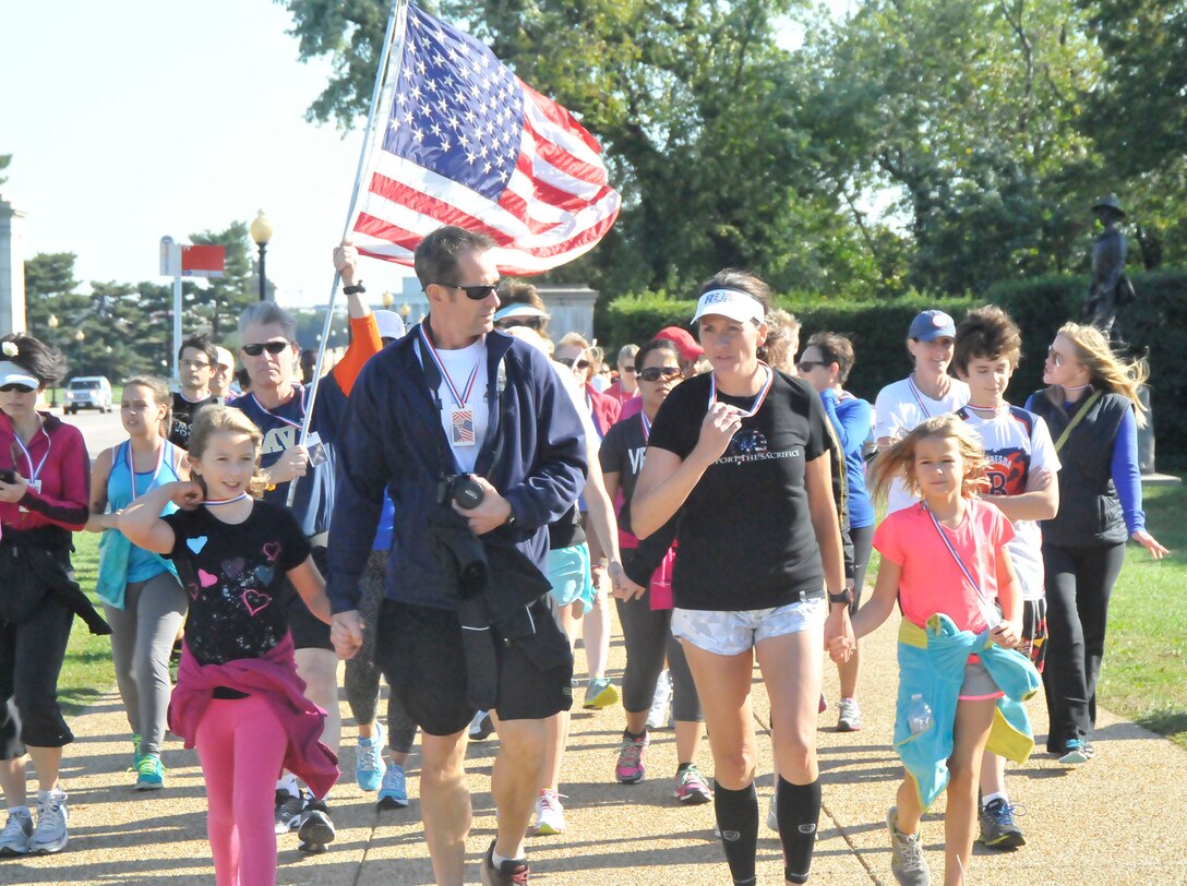 Flanked by daughter Evelyn, far left, husband Pat, center, and daughter Lillian, right, and Valor Run lead runner Navy Reserve Capt. Nancy Lacore particiated in a 160-mile run through Virigina from Memorial Bridge to the Women in Military Service for America Memorial in Washington, D.C., Oct. 18, 2014. The six-day run completed by Lacore was a memorial run to remember 160 service women killed in Afghanistan or Iraq. 