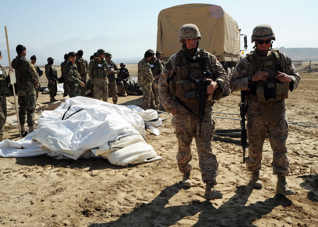 U.S. Navy Chief Petty Officer Kevin Cassidy, left, and Chief Petty Officer Samuel Beauchamp review tent construction with members of the Afghan national engineer brigade during a field training exercise on Kabul Military Training Center in Kabul, Afghanistan, Oct. 19, 2014.  Cassidy and Beauchamp are assigned to Naval Mobile Construction Battalion 25.