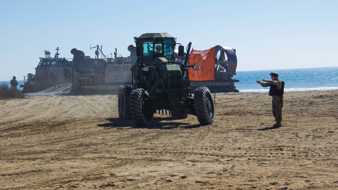 A Sailor with Beach Master Unit 1 guides heavy machinery off a Landing Craft, Air Cushions while performing a ship-to-shore drill during exercise Pacific Horizon 2015 aboard Marine Corps Base Camp Pendleton, Calif., Oct 23, 2014. PH 15 is a scenario driven, simulation supported crisis response exercise designed to improve 1st Marine Expeditionary Brigade's and Expeditionary Strike Group 3's interoperability and strengthen Navy-Marine Corps relations by conducting an in-stream Maritime Prepositioning Force offload of equipment by providing host country civil-military security assistance, and by conducting infrastructure restoration support from Oct. 20-28. 