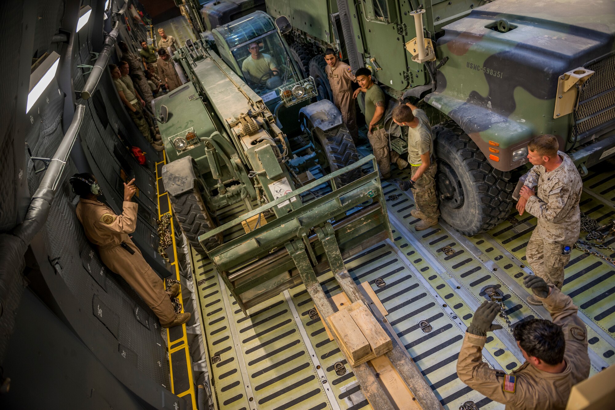 Airmen from the 9th Airlift Squadron and 455th Expeditionary Aerial Port Squadron with Marines from the Marine Expeditionary Brigade prepare to load vehicles into a C-5M Super Galaxy Oct. 6, 2014 at Camp Bastion, Afghanistan. Airmen and Marines loaded more than 266,000 pounds of cargo onto the C-5M as part of retrograde operations in Afghanistan. Aircrews for the retrograde operations, managed by the 385th Air Expeditionary Group Detachment 1, surpassed 11 million pounds of cargo transported in a 50-day period. During this timeframe, crews under the 385th AEG broke Air Mobility Command’s operational cargo load record five times. The heaviest load to date is 280,880 pounds. (U.S. Air Force photo by Staff Sgt. Jeremy Bowcock)