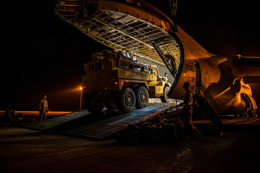 Airmen from the 9th Airlift Squadron and 455th Expeditionary Aerial Port Squadron with Marines from the Marine Expeditionary Brigade prepare to load vehicles into a C-5M Super Galaxy Oct. 6, 2014, at Camp Bastion, Afghanistan. Airmen and Marines loaded more than 266,000 pounds of cargo onto the C-5M as part of retrograde operations in Afghanistan. Aircrews for the retrograde operations, managed by the 385th Air Expeditionary Group Detachment 1, surpassed 11 million pounds of cargo transported in a 50-day period. During this time frame, crews under the 385th AEG broke Air Mobility Command’s operational cargo load record five times. The heaviest load to date is 280,880 pounds. (U.S. Air Force photo by Staff Sgt. Jeremy Bowcock)