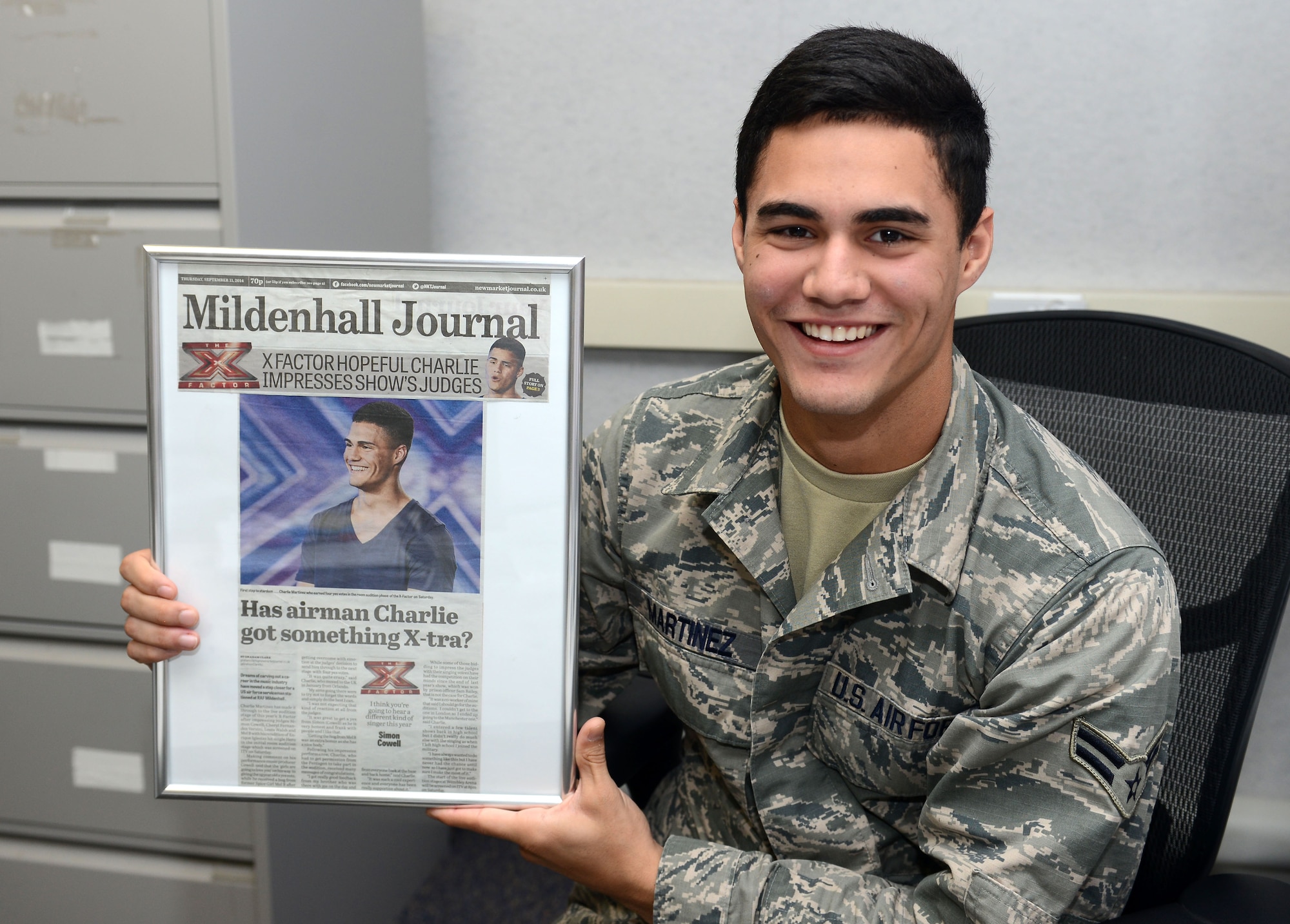 Airman 1st Class Charlie Martinez, 100th Force Support Squadron force management apprentice from Orlando, Fla., poses for a photograph with a newspaper clipping of himself Oct. 15, 2014, on RAF Mildenhall, England. The clipping was from Martinez’s time on X Factor United Kingdom, a televised British singing competition. (U.S. Air Force photo/Senior Airman Kate Maurer)