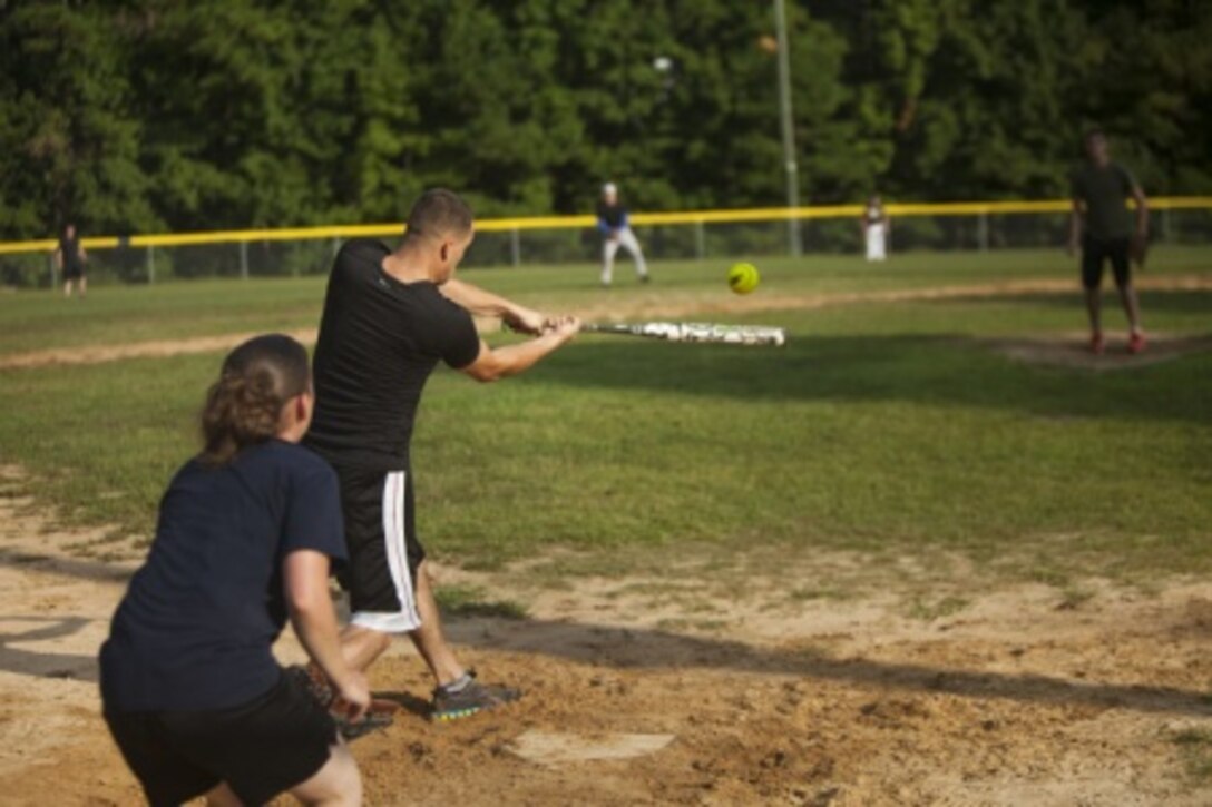 Engineer equipment mechanic swings at a softball in a game against another unit.