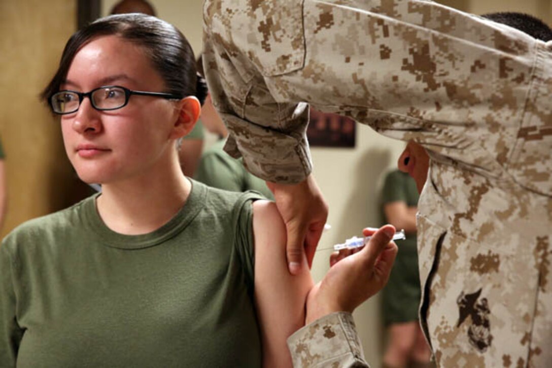 Lance Cpl. Nancy Rascon, administrative specialist, receives a flu shot by Seaman Sabas Hernandez, medical reviewer, at Yale Hall on Oct. 22, 2013. Ninety percent of the Marine Corps is required to receive the flu immunization by Dec. 16, 2013.
