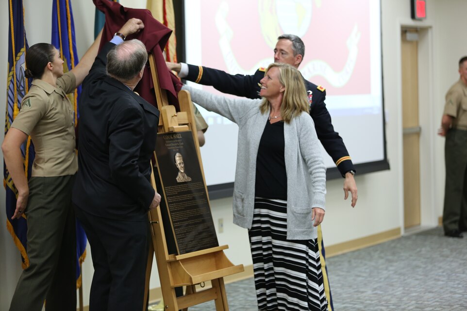 Students from the Defense Language Institute Foreign Language Center, Congressman Sam Farr and Col. David K. Chapman, commandant of the Defense Language Institute Foreign Language Center, assist Col. Donald G. Cook’s daughter unveil his plaque during the Cook Hall dedication aboard Presidio of Monterey, Oct. 17, 2014. (Photo by Pfc. Medina Ayala-Lo)