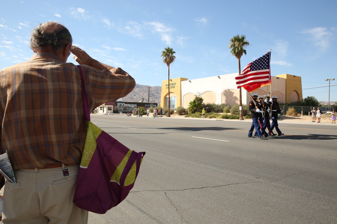 A member of the Twentynine Palms community salutes the Combat Center Color Guard as they pass in review with "Old Glory" and the Marine Corps flag during the Pioneer Days Parade, hosted in the city of Twentynine Palms, Calif., Oct. 18, 2014.
