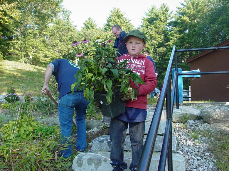 A young participant carries flowers for planting at West Hill Dam, Uxbridge, Mass., during a National Public Lands Day event.