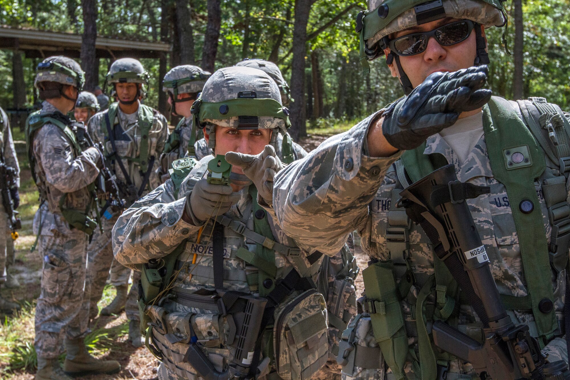 Senior Airman Dennis P. Novello, holding compass, provides maneuvering directions to Senior Airman Craig M. Thompson, as the 108th Security Forces Squadron team enters the woods for scenario based training at Joint Base McGuire-Dix-Lakehurst, N.J., Sept. 14, 2014. The Security Forces Airmen practiced land navigation, weapons proficiency and squad maneuvering tactics during September's unit training assembly. (U.S. Air National Guard photo by Master Sgt. Mark C. Olsen/Released)
