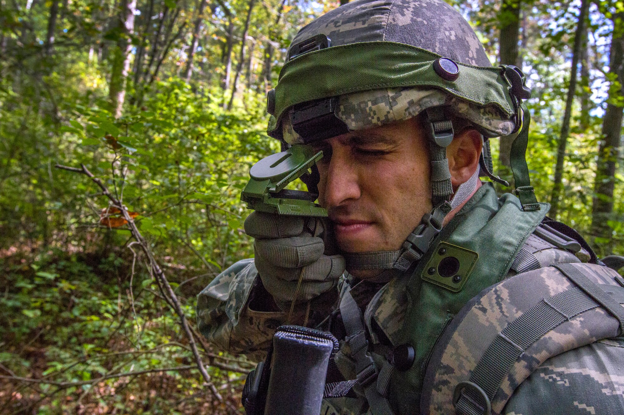 Senior Airman Dennis P. Novello, shoots an azimuth as the 108th Security Forces Squadron team moves through the woods to the military operations in urban terrain facility at Joint Base McGuire-Dix-Lakehurst, N.J., Sept. 14, 2014. Security Forces Airmen practiced land navigation, weapons proficiency and squad maneuvering tactics during September's unit training assembly. (U.S. Air National Guard photo by Master Sgt. Mark C. Olsen/Released)