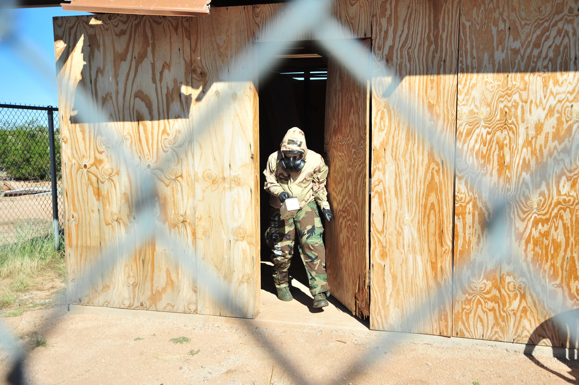 U.S. Air Force Senior Airman Jenna Schaub, 355th Civil Engineer Squadron emergency management journeyman, walks out of a structure while wearing mission oriented protective posture gear during an exercise at Davis-Monthan Air Force Base, Ariz., Oct. 23, 2014.  Schaub was challenged to locate the source of simulated radiation within the structure in order for her to team continue to the next station. (U.S. Air Force Photo by Airman 1st Class Chris Massey/Released)