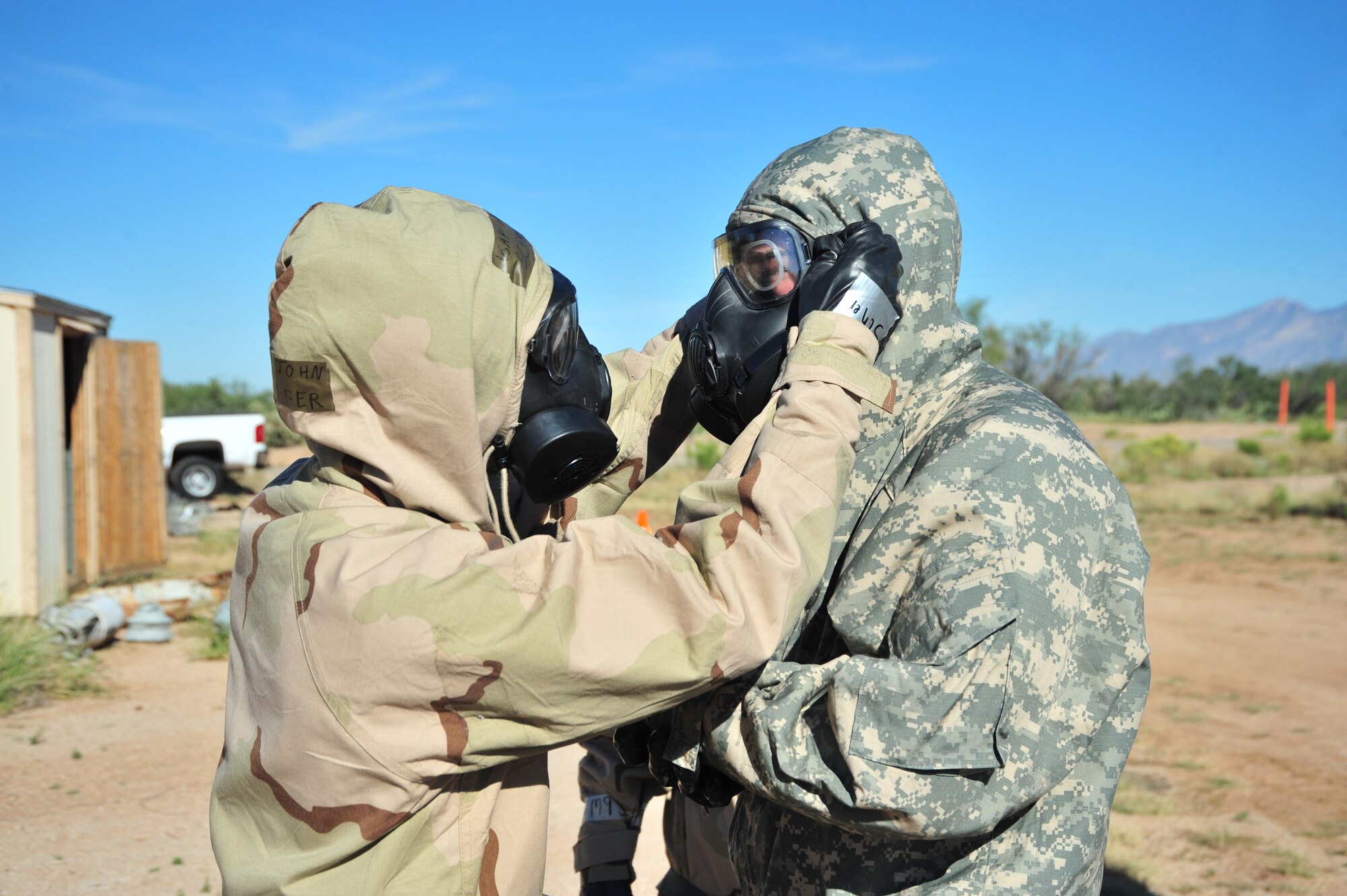 Two team members perform a buddy check to ensure that each has a proper seal on their mission oriented protective posture gear during a competition at Davis-Monthan Air Force Base, Ariz., Oct. 23, 2014.  Each team raced to locate and complete a series of 12 tasks that tested the participants’ wartime and contingency skillsets. (U.S. Air Force Photo by Airman 1st Class Chris Massey/Released)
