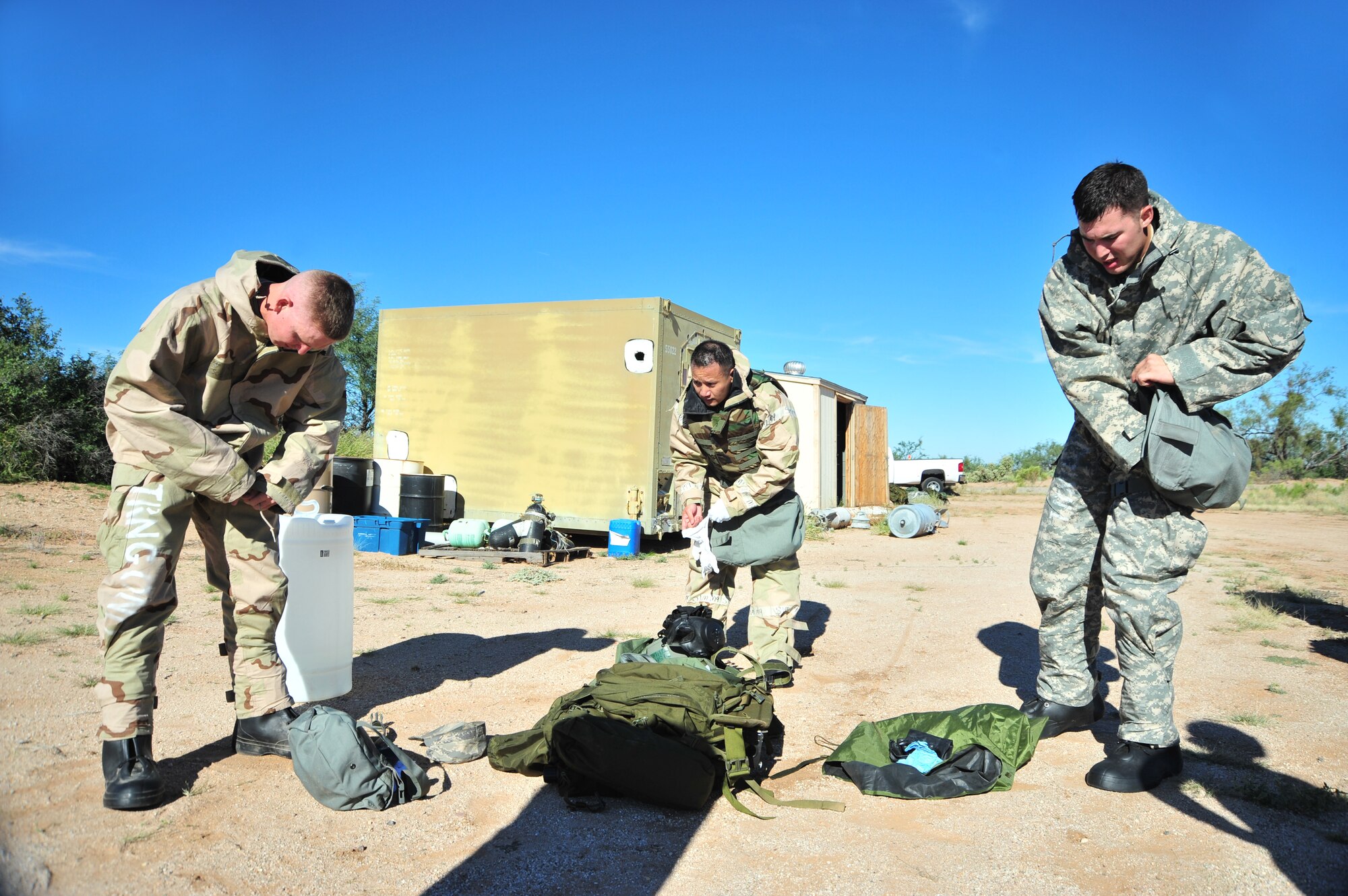 Team members rush to put on mission oriented protective posture gear during an exercise at Davis-Monthan Air Force Base, Ariz., Oct. 23, 2014.  During this station, the teams were given the option to complete a MOPP worksheet or don MOPP level four gear without making any mistakes.  (U.S. Air Force Photo by Airman 1st Class Chris Massey/Released)