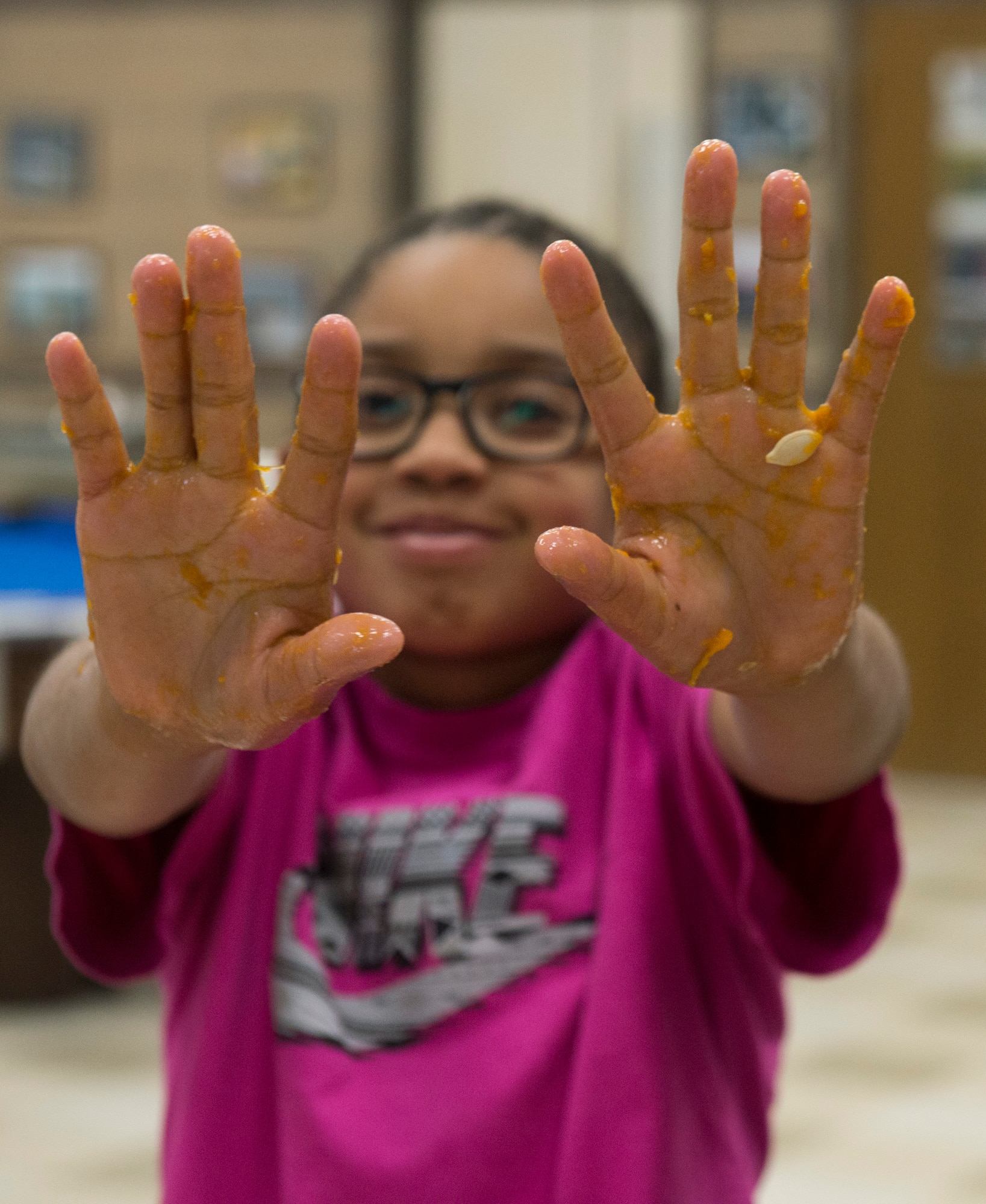 Alexis Dunlap shows off her slime-covered hands, after having finished scooping the seeds out of her pumpkin at the Youth Center at Mountain Home Air Force Base, Idaho, Oct. 22, 2014. The children went all-in despite the messiness that came with the fun activity. (U.S. Air Force photo by Airman 1st Class Jessica H. Smith/RELEASED)