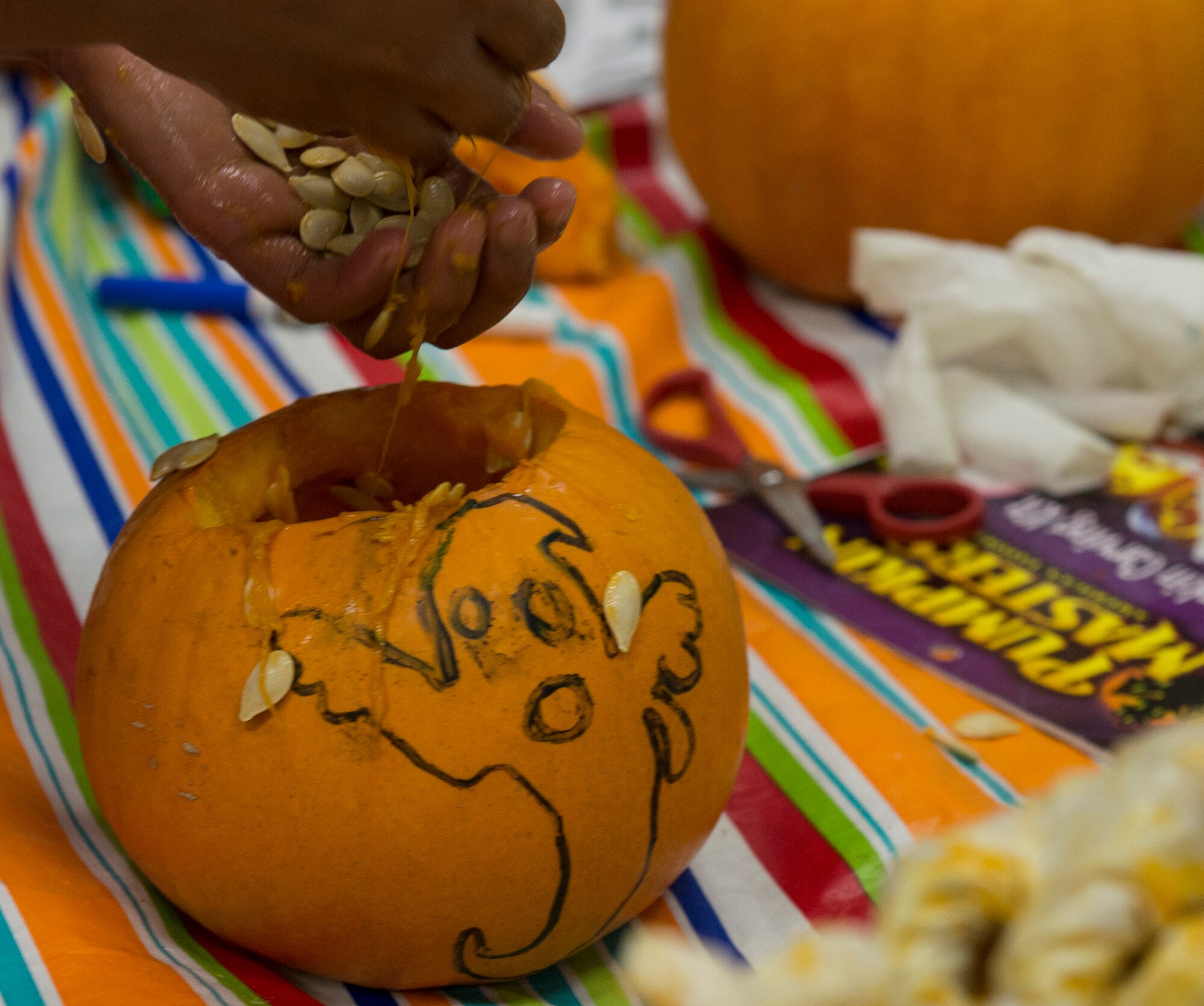 Having finished her design, Alexis Dunlap scoops out pumpkin seeds at the Youth Center at Mountain Home Air Force Base, Idaho, Oct. 22, 2014. Some children skipped carving out their design due to their eagerness to get to the messy part. (U.S. Air Force photo by Airman 1st Class Jessica H. Smith/RELEASED)