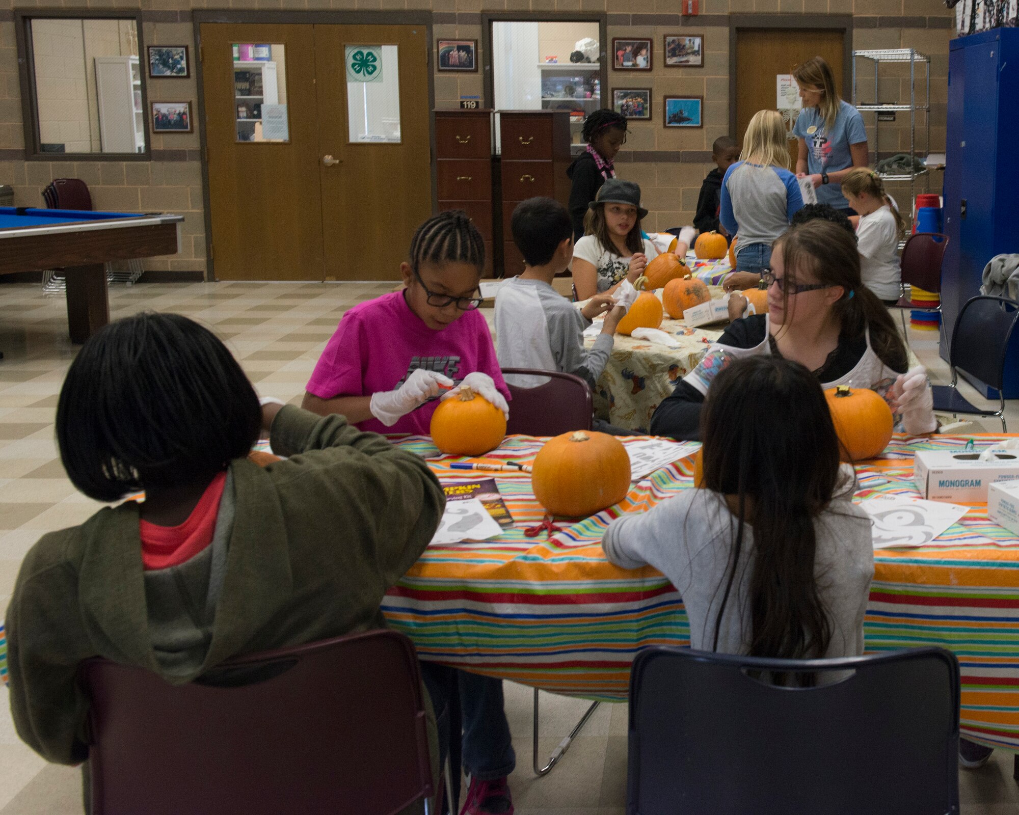 A group of children carve pumpkins at the Youth Center at Mountain Home Air Force Base, Idaho, Oct. 22, 2014. The Youth Center offers many activities for children to participate in. (U.S. Air Force photo by Airman 1st Class Jessica H. Smith/RELEASED)