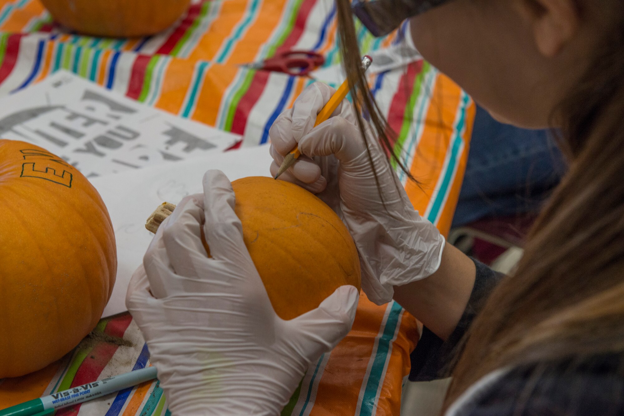 Topanga Auger focuses all her attention on drawing her design onto the pumpkin at the Youth Center at Mountain Home Air Force Base, Idaho, Oct. 22, 2014. Many of the children chose to draw their own design rather than trace a stencil. (U.S. Air Force photo by Airman 1st Class Jessica H. Smith/RELEASED)