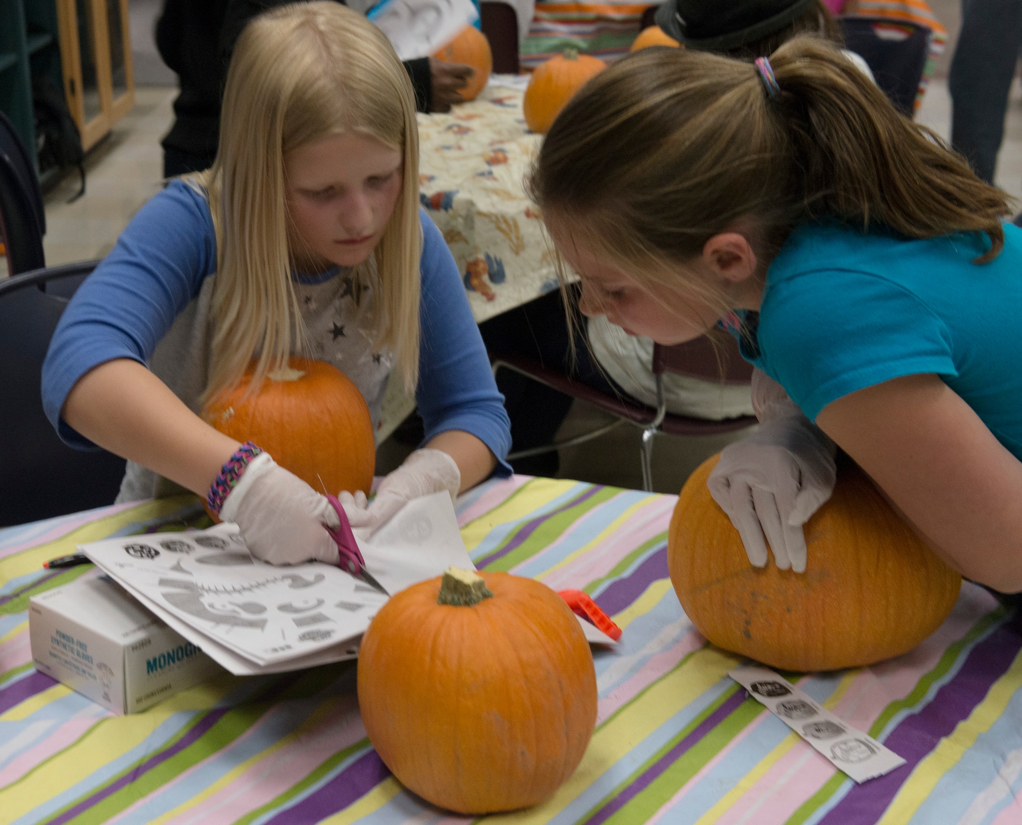 Kaitlyn Harrison and Allison Wheeler cut out a pumpkin design together at the Youth Center at Mountain Home Air Force Base, Idaho, Oct. 22, 2014. The Youth Center held a pumpkin-carving event to involve children in Halloween festivities. (U.S. Air Force photo by Airman 1st Class Jessica H. Smith/RELEASED)