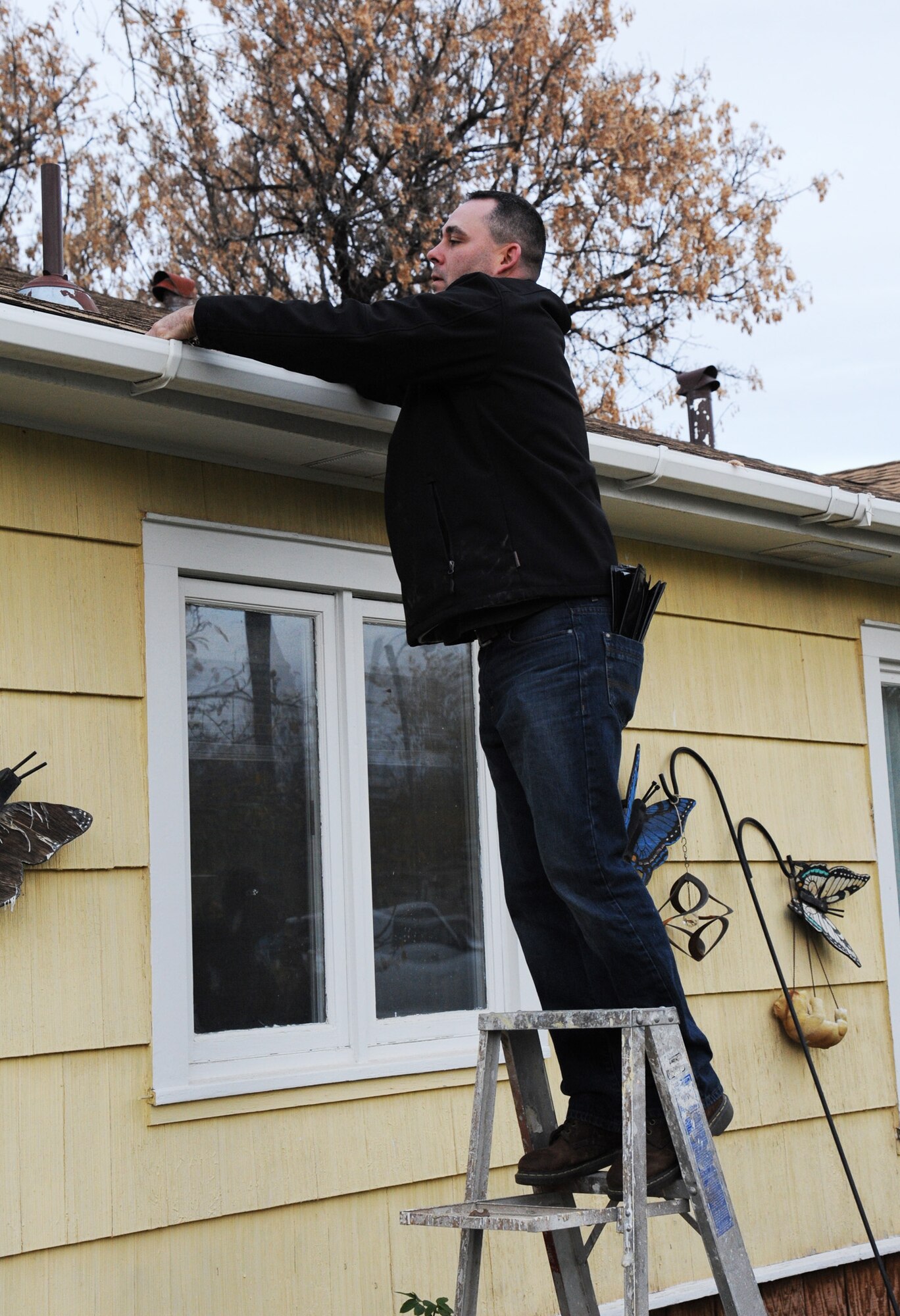 Master Sgt. Paul Watts, 341st Munitions Squadron first sergeant, removes leaves from a gutter at a house in Great Falls, Mont., Oct. 24.  Watts was one of nearly 50 volunteers that showed up to participate in the annual Day of Caring. (U.S. Air Force photo/Christy Mason)