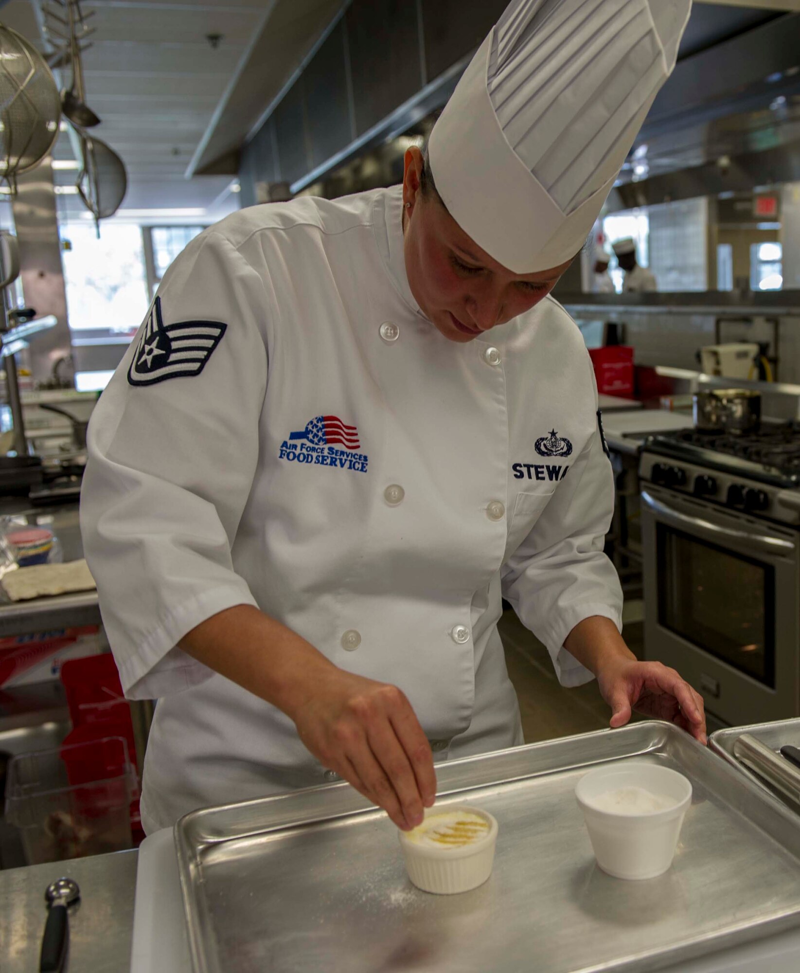 Staff Sgt. Sheryl Stewart, a 647th Force Support Squadron Airman assigned to the Joint Culinary Arts Team Hawaii, sprinkles sugar on a poached pear crème brulee dessert in the training kitchen at Schofield Barracks Oct. 22, 2014. Stewart will join 15 Soldiers, Sailors and Marines from around the island to face off in the annual Military Culinary Arts Competitive Training Event in Fort Lee, Va., next year. (U.S. Air Force photo by Tech. Sgt. Terri Paden)
