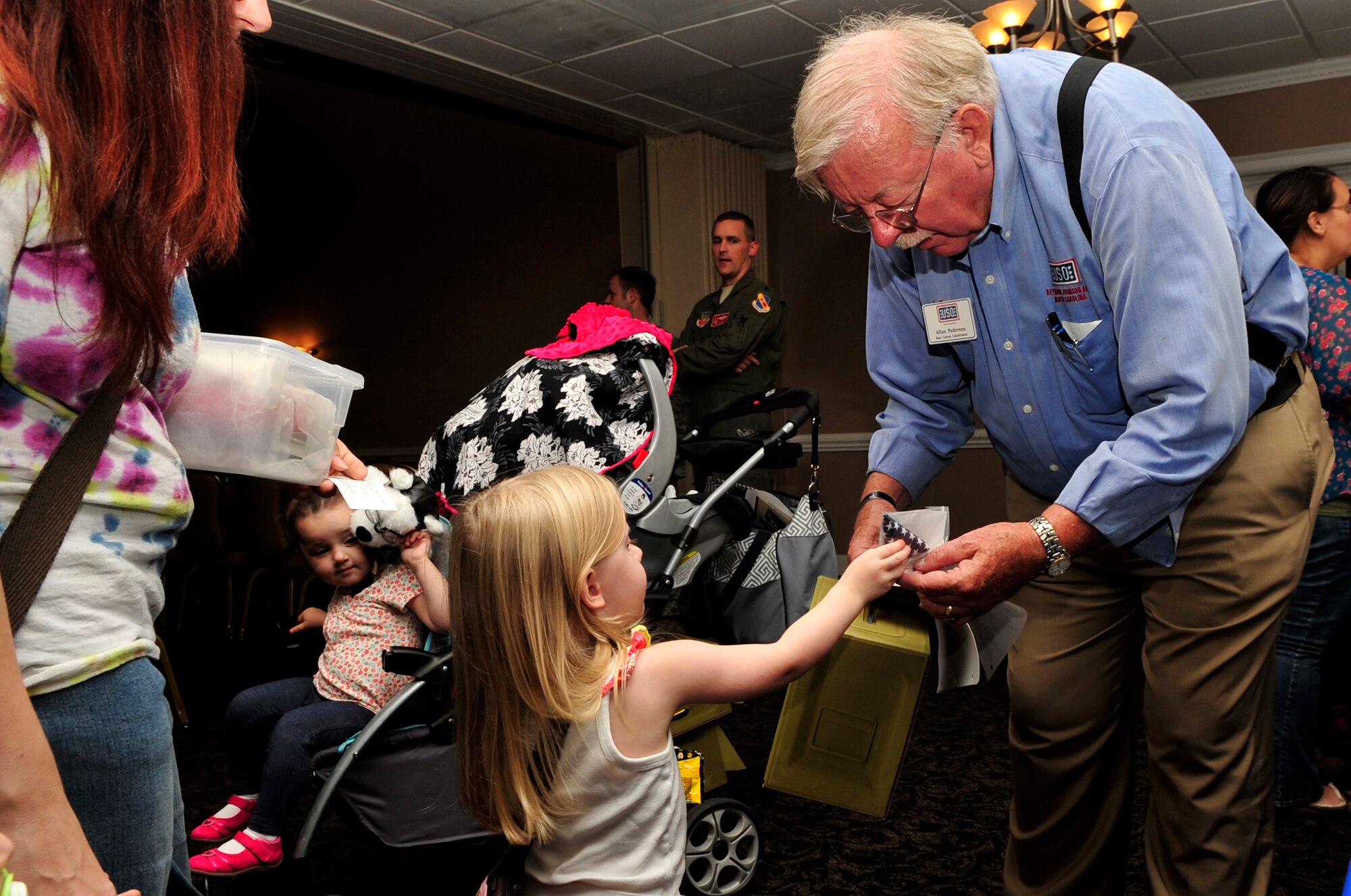 Allan Pederson, base liaison coordinator for the USO, hands out care packages with teddy bears to children during a “Hearts Apart” event Oct. 24, 2014, at Seymour Johnson Air Force Base, North Carolina. The event focused on relieving the pressures families sustain when a member is deployed and served as a venue to ensure families are connected with the wing’s many helping agencies and resources. (U.S. Air Force photo/Airman 1st Class Shawna Keyes)
