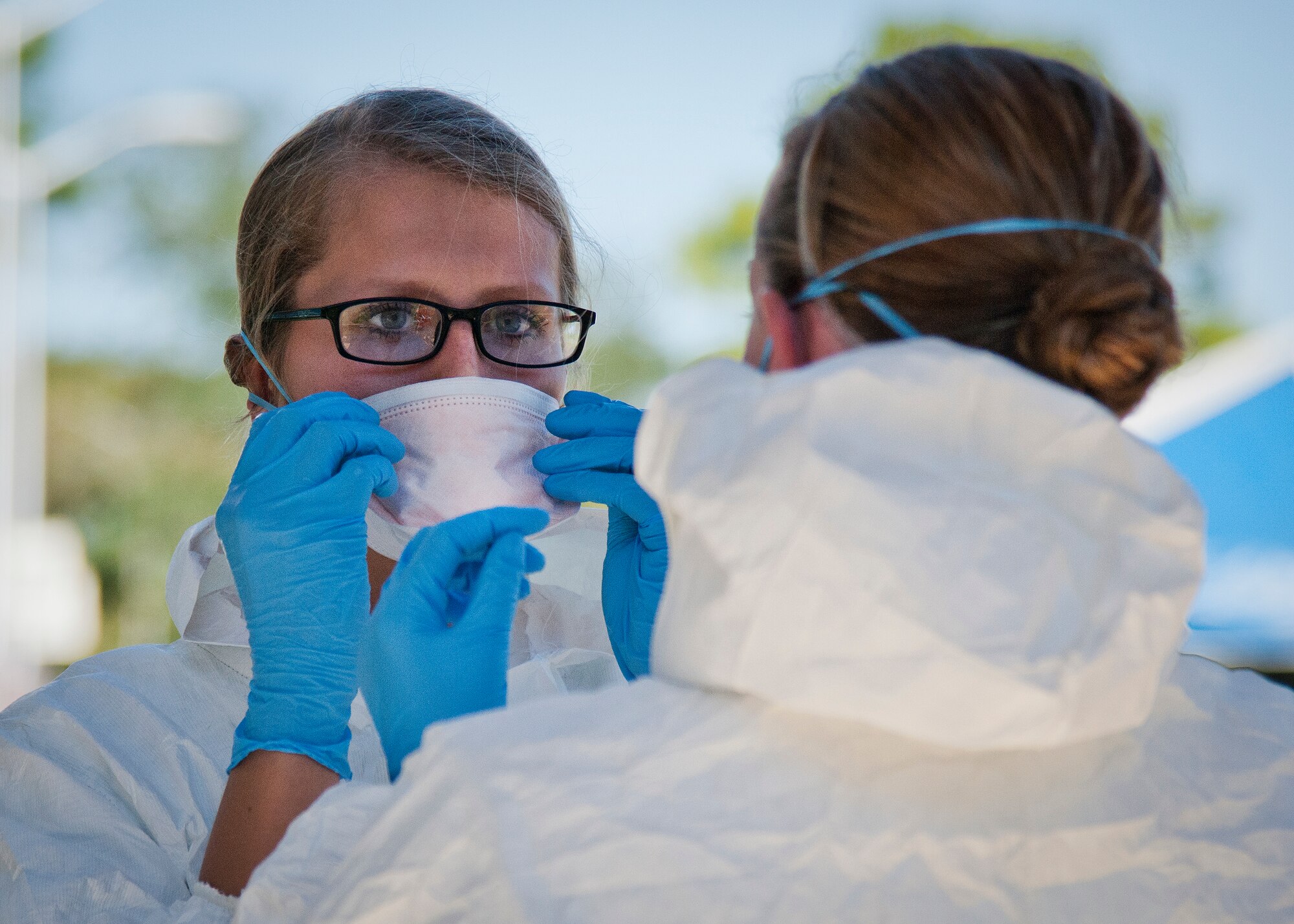 Airman 1st Class Nanci Hause, 96th Medical Group, receives help donning her protective mask during a disease containment exercise at Eglin Air Force Base, Fla., Oct. 22.  The base’s medical personnel performed the specific procedures required in the event of an outbreak in the local area and on base.  (U.S. Air Force photo/Samuel King Jr.)