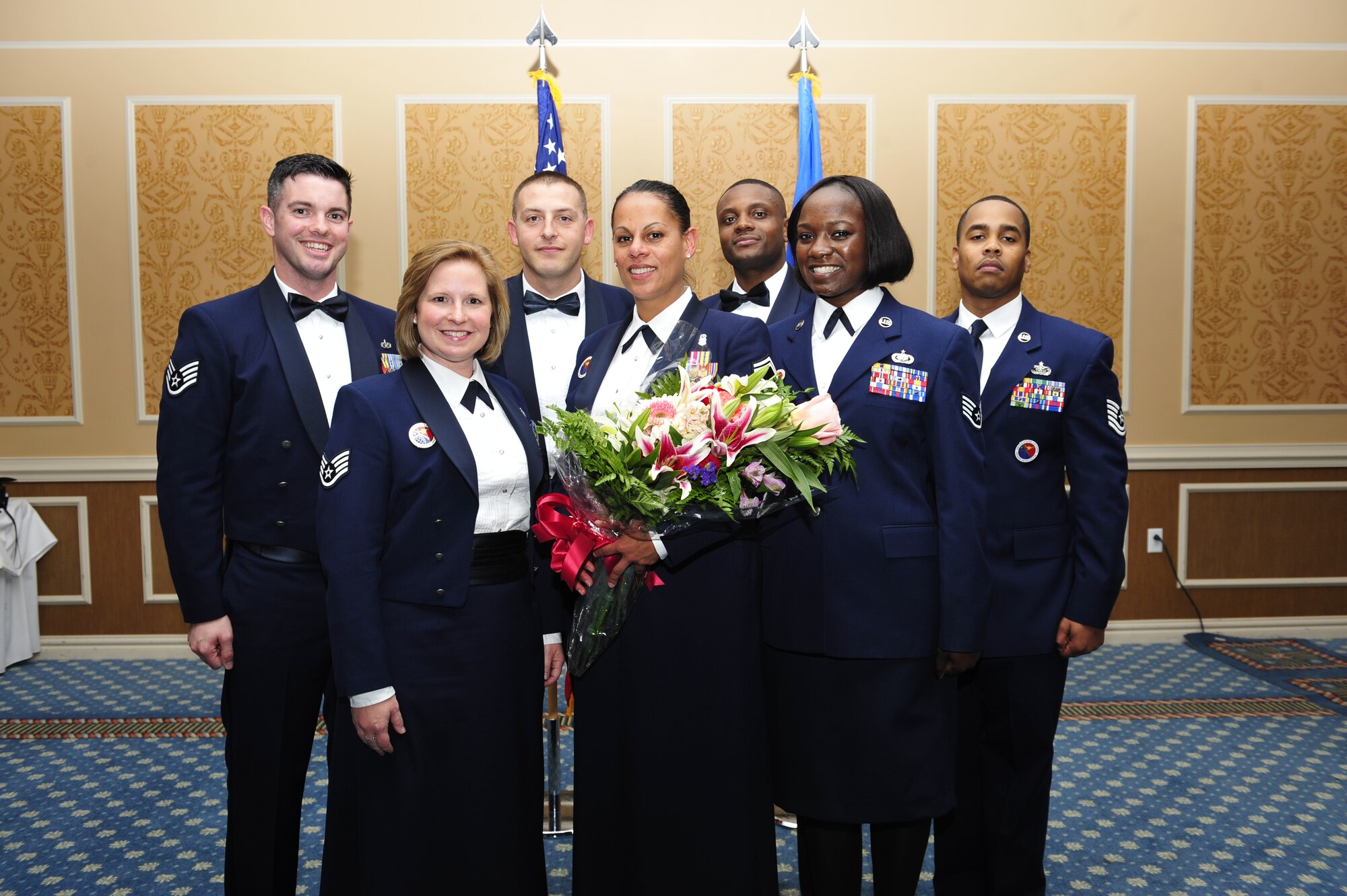 U.S. Air Force Senior Master Sgt. Leyla Gillett, former Langley Air Force Base Airman Leadership School commandant, center, is presented flowers from the ALS staff after an ALS graduation, Oct. 24, 2014. Gillett worked closely with her staff throughout her four years as the commandant, and ensured they all communicated to produce new noncommissioned officers that embody the Air Force core values.  (U.S. Air Force photo by Airman 1st Class Breonna Veal/Released)