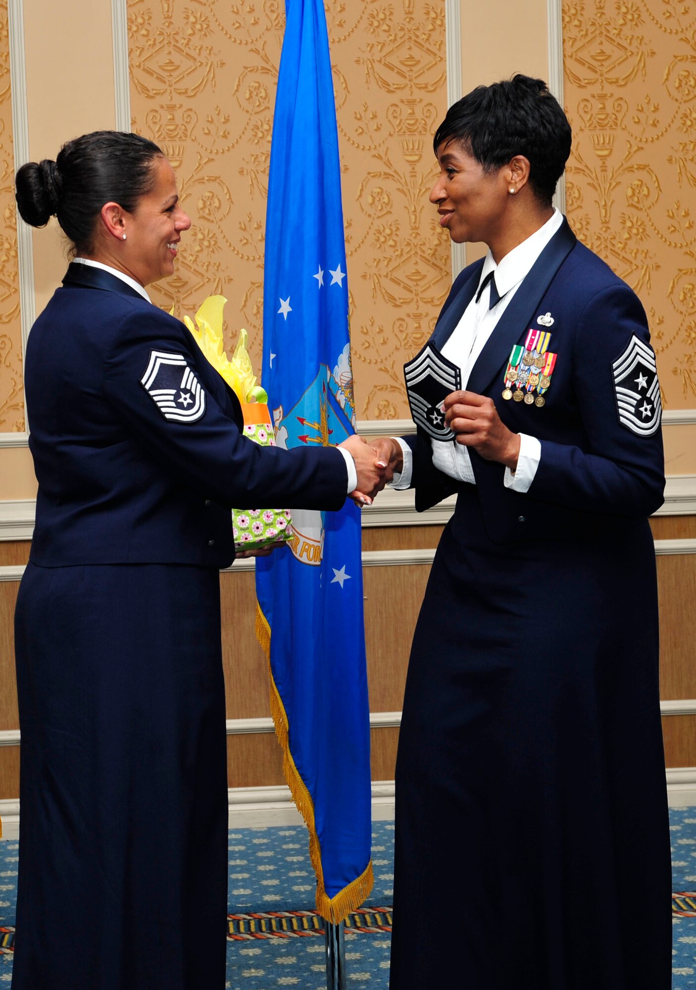 U.S. Air Force Chief Master Sgt. Trae King, 633rd Air Base Wing command chief, right, gifts U.S. Air Force Senior Master Sgt. Leyla Gillett, former Langley Air Force Base Airman Leadership School commandant, a pair of her chief master sergeant stripes at an ALS graduation, Oct. 24, 2014. King gave Gillett the stripes because she said she has confidence the former commandant will promote to her next rank. She was the commandant for four years. ( (U.S. Air Force photo by Airman 1st Class Breonna Veal/Released)