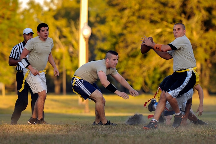 Staff Sgt. Jonathan Haney, 437th Aircraft Maintenance Squadron dedicated crew chief, sets up to throw while Airman 1st Class Ulises Zamora, 437th AMXS crew chief (left) and Staff Sgt. Williams McDevitt, 437th AMXS instrument and flight controls systems technician, provide coverage during the first Air Base intramural flag football game of the season Oct. 21, 2014, at Joint Base Charleston, S.C. The 628th Civil Engineer Squadron beat AMXS 24-14. (U.S. Air Force photo/Staff Sgt. Renae Pittman)