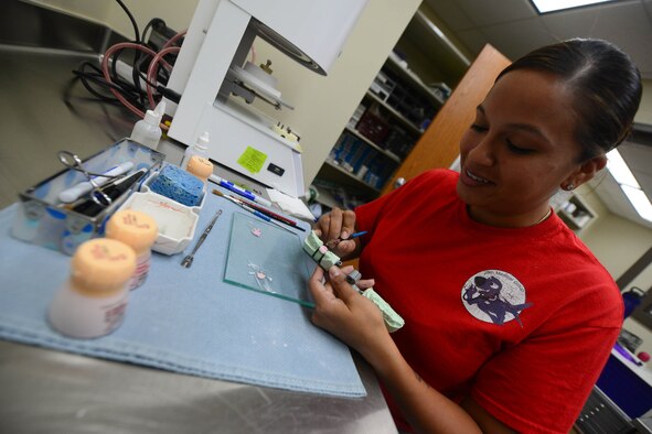 Staff Sgt. Gina Rosales, 28th Medical Operation Squadron dental laboratory technician, shapes a porcelain crown onto a patient’s dental impression at Ellsworth Air Force Base, S.D., Oct. 17, 2014.The lab supports the dental clinic by producing comfortable and accurate oral appliances for active-duty base personnel. (U.S. Air Force photo by Senior Airman Zachary Hada/Released) 