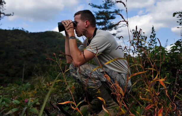 U.S. Air Force Senior Airman Charlie Hegwer, 51st Communication Squadron cable antenna systems journeyman, looks for simulated opposing forces during a combat search and rescue training scenario at an off base training site, Republic of Korea, Oct. 14, 2014. The training was conducted to better prepare the Airmen involved to locate and recover isolated personnel in remote areas with different terrain. (U.S. Air Force photo by Senior Airman David Owsianka/Released)