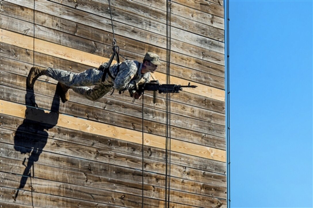 An Army Ranger carrying an M249 light machine gun rappels down a wall as part of a demonstration during a Ranger school graduation on Fort Benning, Ga., Oct. 17, 2014.
