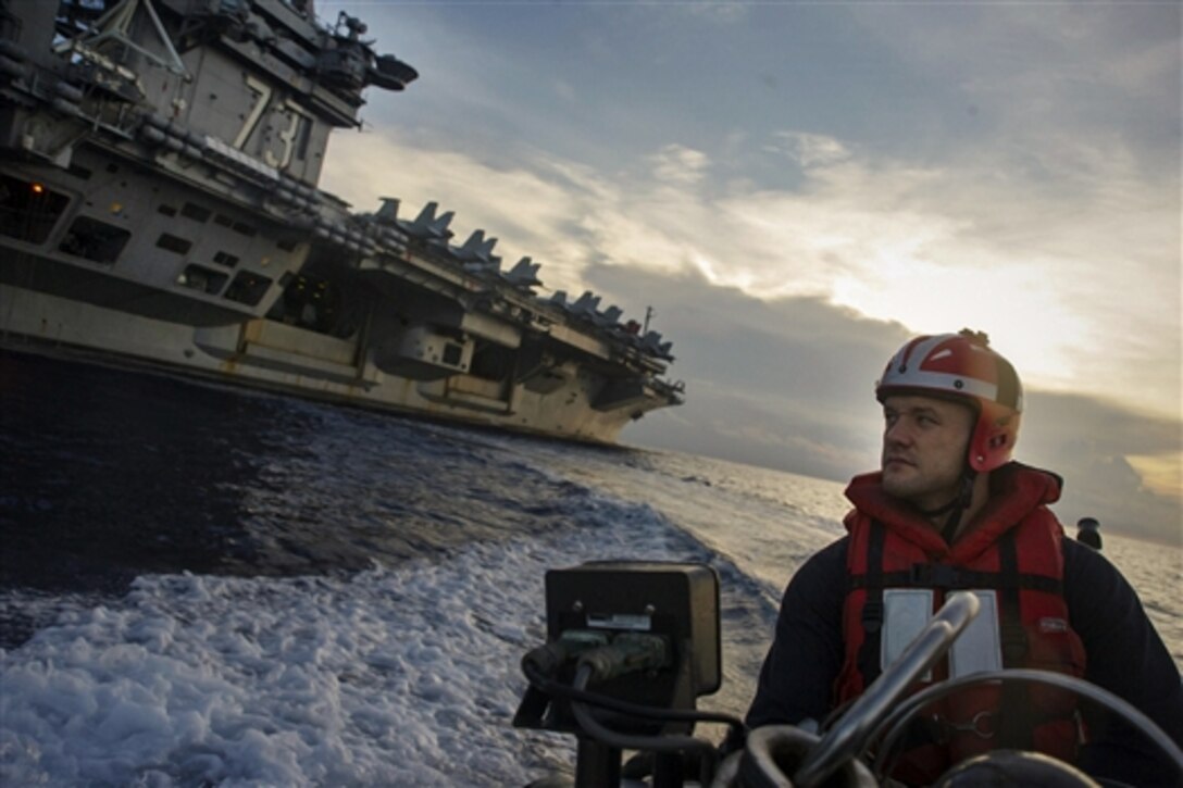 U.S. Navy Petty Officer 2nd Class Joshua Dingman maneuvers a rigid-hull inflatable boat near the aircraft carrier USS George Washington during a man overboard drill in the South China Sea, Oct. 21, 2014. The George Washington was underway in the U.S. 7th Fleet area of responsibility supporting maritime security operations and theater security cooperation efforts. 