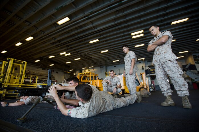 Marines with Security Platoon, Maritime Raid Force, 24th Marine Expeditionary Unit, perform practice drills with an M240B machine gun in the hangar bay aboard the USS Iwo Jima, Oct. 25, 2014. The Marines are participating in their final exercise as part of Composite Training Unit Exercise before their deployment at the end of the year. (U.S. Marine Corps photo by Cpl. Todd F. Michalek)